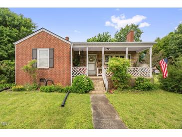Charming red brick home featuring a cozy front porch and a well-maintained lawn with mature landscaping at 625 Columbia Ave, Burlington, NC 27217