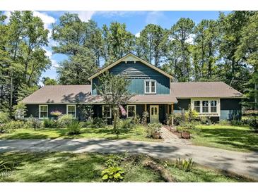 Inviting two-story home with beautiful landscaping, a charming front porch, and a long driveway lined by mature trees at 8156 Nc 42 Hwy W, Kenly, NC 27542