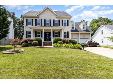Traditional two-story home with a manicured lawn, black shutters, and an attached two-car garage at 113 Sycamore Ridge Ln, Holly Springs, NC 27540