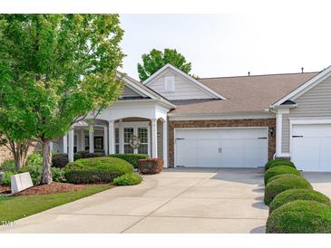 Charming home with a two-car garage, stone accents, well-manicured landscaping, and a welcoming covered front porch at 128 Arvind Oaks Cir, Cary, NC 27519