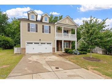 Charming two-story home boasts a well-manicured lawn, attached garage, and inviting covered porch at 143 Thornbury St, Clayton, NC 27527