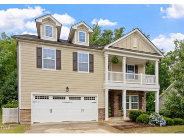 Charming two-story home with a white garage door, beautiful plants, and second story porch at 143 Thornbury St, Clayton, NC 27527