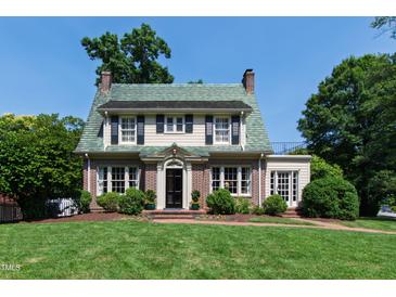 Charming brick home featuring a distinctive green tile roof, manicured lawn, and classic architectural details at 1700 St Marys St, Raleigh, NC 27608