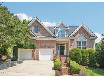 Beautiful two-story brick home with a manicured lawn, mature trees, and an attached garage at 1817 Wysong Ct, Raleigh, NC 27612