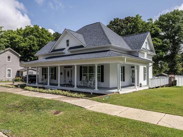 Charming two-story home features a spacious front porch, classic columns, and beautifully landscaped yard at 212 W Church St, Benson, NC 27504