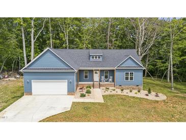 Charming blue home featuring a manicured front yard, garage, and inviting front porch with rocking chairs at 5550 Mountain Trl, Snow Camp, NC 27349