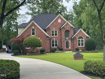 Beautiful brick two-story home with well-manicured landscaping, mature trees, and a curved driveway at 6553 Vintage Ridge Ln, Fuquay Varina, NC 27526