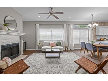 Bright living room featuring a fireplace, ceiling fan, and large windows dressed with white curtains at 107 Covington Dr, Chapel Hill, NC 27514