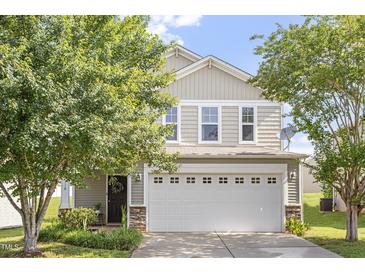 Charming two-story home with neutral siding and a two car garage, framed by mature trees in the front yard at 110 Bray Dr, Mebane, NC 27302
