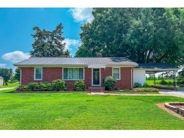Charming brick home with metal roof, lush landscaping and a convenient carport at 111 Dee Long Rd, Roxboro, NC 27574