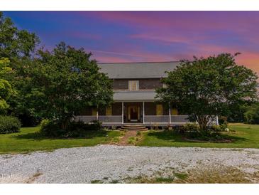 Charming two-story brick home with a inviting front porch, beautiful trees, and ample outdoor space at 1770 Gentry Ridge Rd, Roxboro, NC 27574