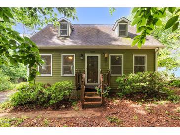 Charming, two-story home featuring dormer windows and a welcoming front porch surrounded by mature landscaping at 1869 Brevard Rd, Graham, NC 27253