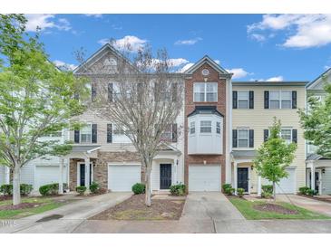 Charming townhomes boast diverse facades, attached garages, and landscaped front yards under a bright blue sky at 3027 Courtney Creek Blvd, Durham, NC 27713