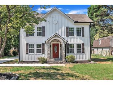 Charming two-story home featuring board and batten siding, a stone front porch, and a red front door at 305 W Canary St, Dunn, NC 28334