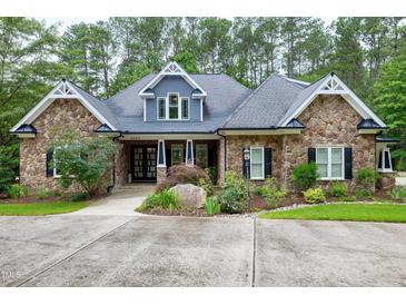 Stunning stone-clad home with beautiful landscaping, mature trees, and a classic architectural design at 4924 Stoneyoak Ln, Raleigh, NC 27610