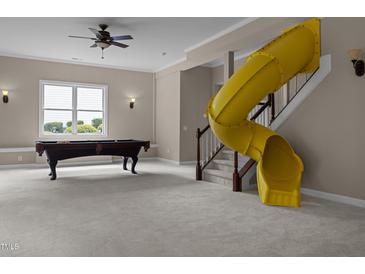 Spacious carpeted basement featuring a pool table and a bright yellow slide leading from the upper level at 7409 Chesley Ln, Durham, NC 27713