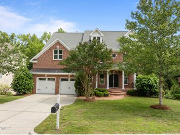 Charming brick home boasts a well-manicured lawn, mature trees, and attached two-car garage at 7409 Chesley Ln, Durham, NC 27713