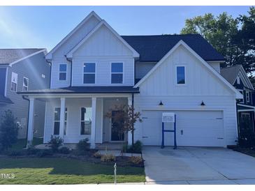 Beautiful two-story home featuring a white exterior, covered porch, and two-car garage at 750 Bachelor Gulch Way, Apex, NC 27523