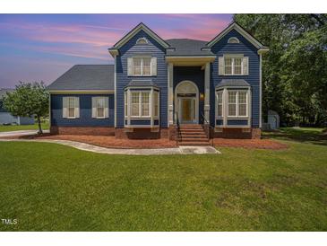 Charming blue two-story home boasts a landscaped front yard, brick foundation, and inviting entrance at 104 Goldleaf Ct, Angier, NC 27501