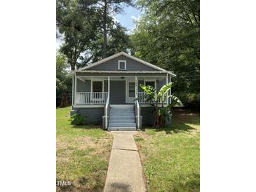 Charming single-story home with a gray exterior, inviting front porch, and mature trees at 108 Herbert St, Durham, NC 27703