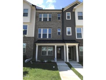 Townhouse exterior showcasing a brick facade, covered porch, and well-maintained landscaping at 115 Ballyliffen Ln, Cary, NC 27519