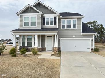 Charming two-story home with gray siding, black shutters, covered porch, and two-car garage at 13 Knotty Pine Lane, Clayton, NC 27520