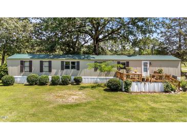 Inviting home with a green metal roof, manicured landscaping, and charming wood deck and railing at 1355 Sykes Rd, Spring Hope, NC 27882