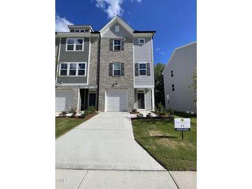 Attractive townhome with brick and siding facade, featuring a one-car garage and well-maintained lawn at 1916 Fishamble St # 22, Fuquay Varina, NC 27526