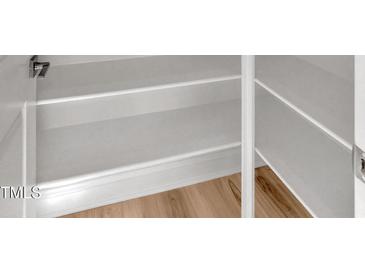 Bright white open closet with adjustable shelves and light wood flooring at 509 Sherron Road # 9, Durham, NC 27703