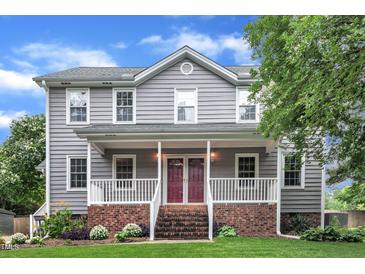 Charming two-story home features a welcoming front porch and well-manicured lawn and red double front doors at 8121 Bentwood Pl, Raleigh, NC 27615