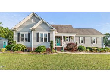 Charming single-story home featuring manicured lawn, gray siding, and a welcoming front porch at 817 Mossy Oak Dr, Fuquay Varina, NC 27526