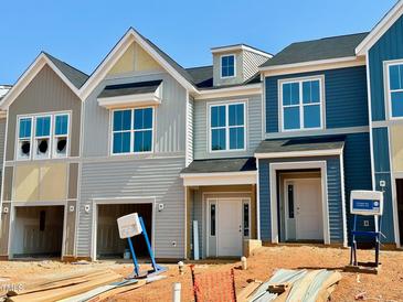 New townhomes featuring attached garages, varied siding colors, and a classic architectural style at 91 Ripple Way # 213, Clayton, NC 27520