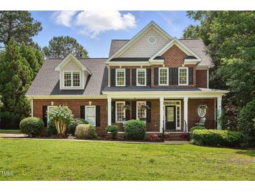 Charming two-story brick home featuring a welcoming front porch, black shutters, and manicured landscaping at 2328 Forestbluff Dr, Fuquay Varina, NC 27526