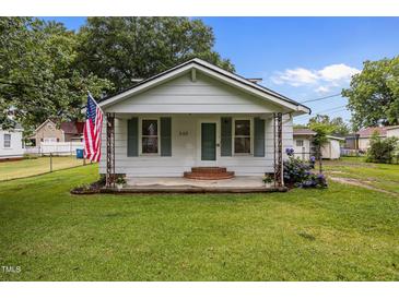 Charming bungalow features a well-manicured lawn, American flag, and a welcoming front porch at 303 N Watauga Ave, Dunn, NC 28334