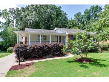 Charming home with white exterior, brick accents, covered porch, and manicured landscaping at 325 Northfield Dr, Raleigh, NC 27609