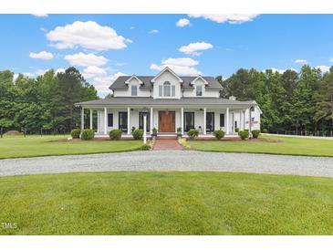 Stunning two-story white home featuring a charming wrap-around porch and a meticulously landscaped front yard at 4737 Uzzle Rd, Rougemont, NC 27572
