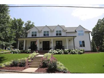 Charming two-story home with a well-maintained lawn, landscaped flower beds, and a welcoming covered front porch at 615 Sampson St, Raleigh, NC 27609