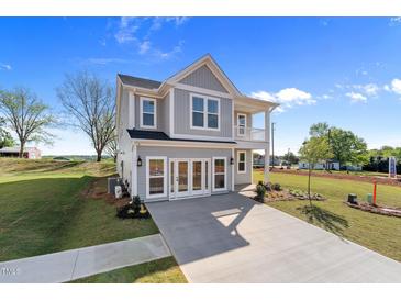 Charming two-story home featuring a covered porch and gray siding, complemented by a well-manicured lawn at 1305 Westerland Way # 17, Durham, NC 27703