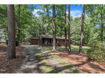 Charming brick home with a cozy front porch, surrounded by mature trees and natural landscaping at 2005 Messer Rd, Raleigh, NC 27603