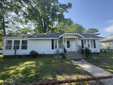 Charming single-story home featuring a well-maintained yard, cozy porch, and lovely curb appeal on a sunny day at 212 S Sixth St, Smithfield, NC 27577