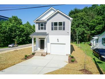 Charming two-story home with gray and white siding, front porch, and a concrete driveway leading to an attached garage at 213 Clement Ave, Oxford, NC 27565