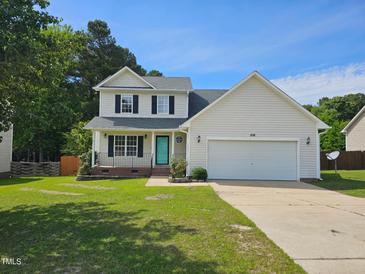 Charming two-story home featuring a well-manicured lawn, attached garage, and inviting turquoise-colored front door at 216 Edgecombe Dr, Spring Lake, NC 28390