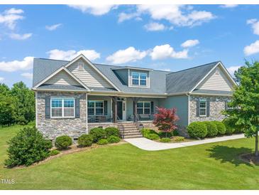 Charming home with stone accents, lush landscaping, and a covered front porch, perfect for enjoying the outdoors at 216 Tarkenton Ct, Clayton, NC 27527