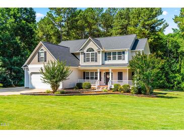 Charming two-story home with a well-manicured lawn, lovely landscaping, and inviting front porch perfect for relaxing at 1054 Contender Dr, Clayton, NC 27520