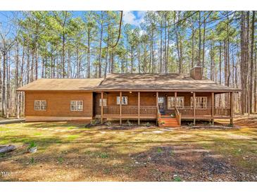 Charming log cabin with a cozy front porch, nestled amongst a backdrop of tall pine trees at 1101 Dimmocks Mill Rd, Hillsborough, NC 27278