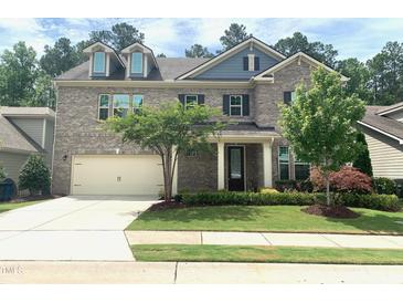 Charming two-story brick home featuring a two-car garage, well-manicured lawn, and inviting front porch at 1205 Capstone Dr, Durham, NC 27713