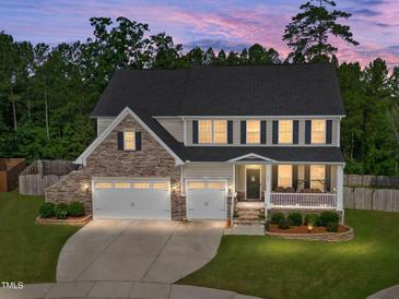 Two-story home with stone accents, a charming front porch with swing, a manicured lawn and a two-car garage at 232 Randleman Ct, Holly Springs, NC 27540