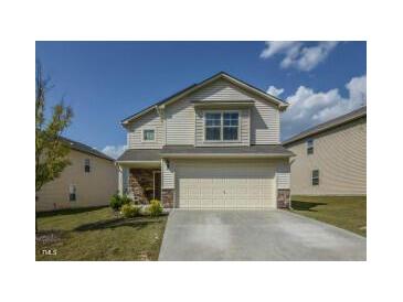 Charming two-story home with a two car garage and a manicured lawn, under a blue partly cloudy sky at 4401 Lyman Ave, Raleigh, NC 27616