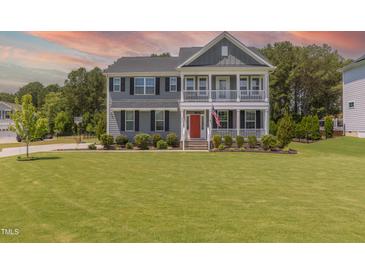 Charming two-story home with a manicured lawn, double porches, and a striking red front door at 470 E Wellesley Dr, Clayton, NC 27520