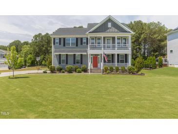 Charming two-story home with a spacious lawn, double porches, and an eye-catching red front door at 470 E Wellesley Dr, Clayton, NC 27520